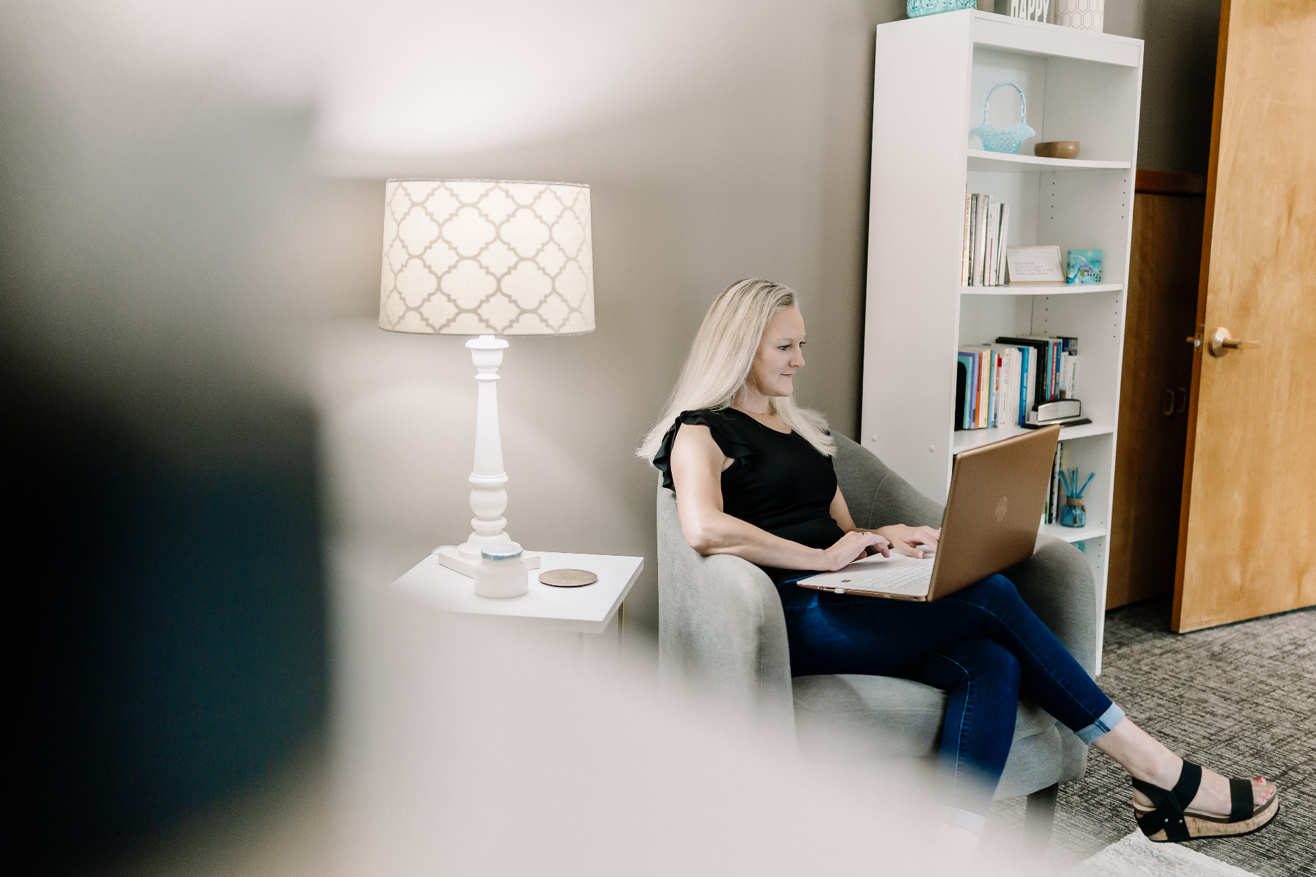 A woman working quietly on a laptop in a softly lit therapy room