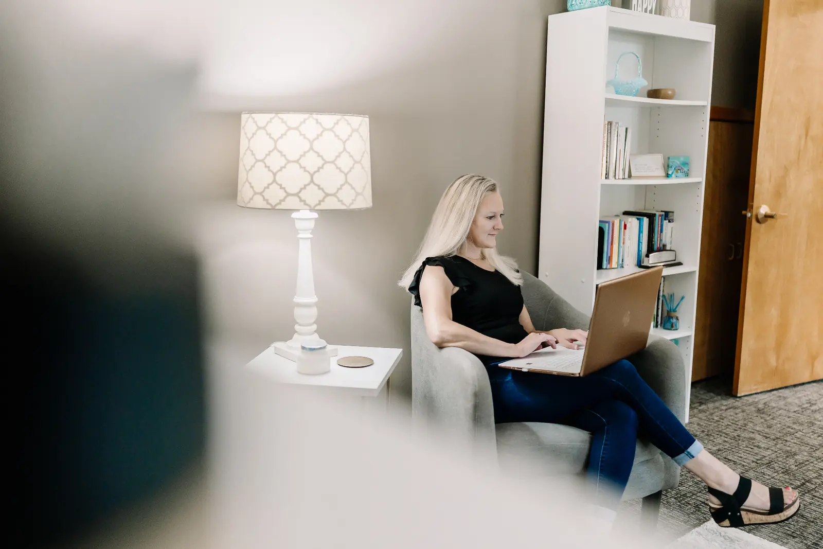 A woman working quietly on a laptop in a softly lit therapy room