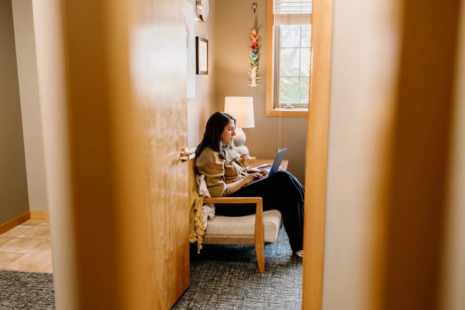 A woman writing on a laptop in a sunlit private office